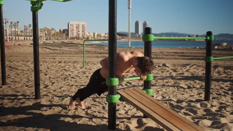 Young-sporty-man-pushing-up-during-functional-training-on-sport-ground-by-the-sea.-Fit-guy-on-workout-outdoor