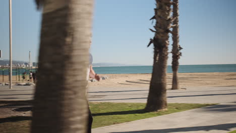 Tracking-shot-of-young-muscular-man-doing-side-flip-and-running-during-workout-in-city-park