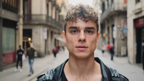 Tracking-out-shot-of-young-handsome-man-intently-looking-in-camera-on-busy-city-street