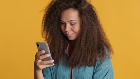 Caucasian-curly-haired-woman-using-smartphone-and-laughing.