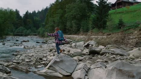 Hiker-walking-on-rocks-at-river