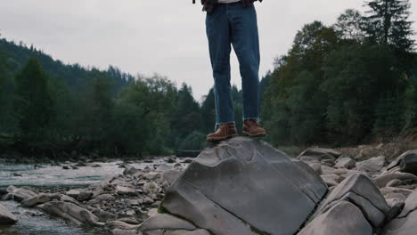 Tourist-standing-on-rock-at-river