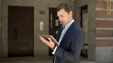 Close-up-view-of-businessman-holding-tablet-on-the-street