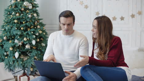 Young-couple-discussing-near-laptop-in-modern-house