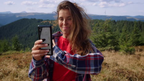 Female-hiker-talking-with-friend-by-video-chat-on-smartphone