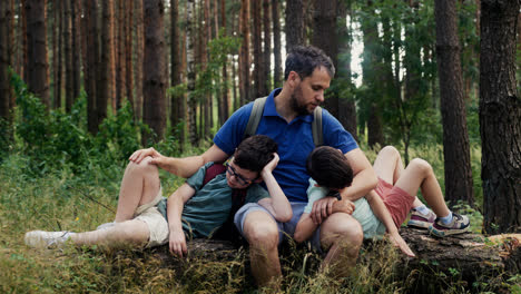Family-sitting-on-trunk-at-the-forest