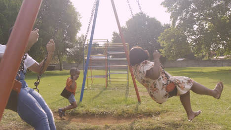 Familia-Jugando-En-Los-Columpios