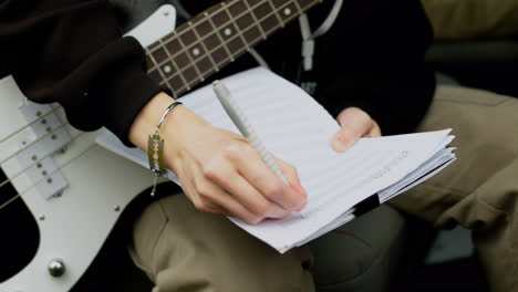 Man-holding-guitar-and-sheet-music