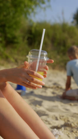 Woman-drinking-juice-at-the-beach