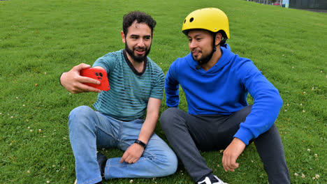 Dos-Hombres-Sentados-En-El-Césped,-Hablando.