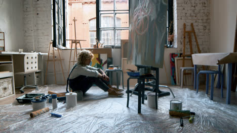 Artist-sitting-in-front-of-painting
