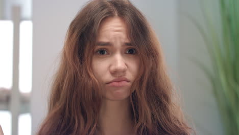 Unhappy-young-woman-touching-and-looking-her-dry-hair