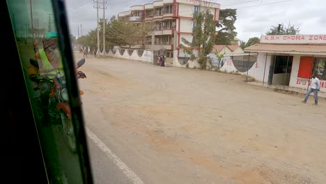 Motorcycle-Rider-On-The-Street-Driving-By-Lumber-Industry-On-The-Roadside-In-Narok,-Kenya