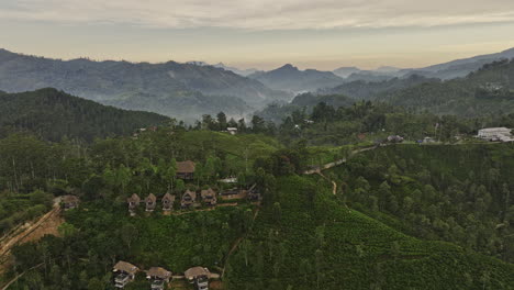 Ella-Sri-Lanka-Aerial-v15-cinematic-drone-flyover-rural-hillside-resort-hotels-surrounded-by-tea-covered-hills,-verdant-valleys-and-mountainous-landscape-at-dawn---Shot-with-Mavic-3-Cine---April-2023