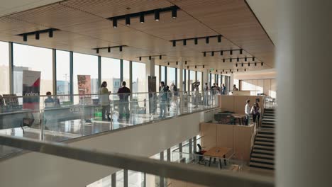 4K-Gimbal-Shot-Rounding-the-Corner-Inside-a-New-Diverse-Architecture-Building-with-a-Trade-Show-Going-on-in-the-Background-Daytime-Interior-and-People-Attendees-Walking-Around-University-Campus