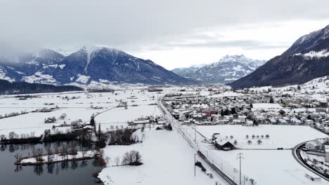 Toma-Aérea-Acercándose-A-La-Aldea-De-Reichenburg-Durante-La-Temporada-De-Nieve-En-Invierno-En-Suiza