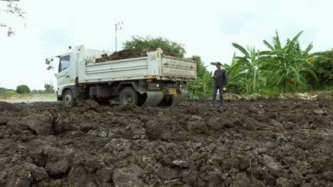 A-dumptruck-dumping-some-muddy-soil-in-a-landfill-in-an-open-field-in-Chachoengsao,-a-province-in-Thailand