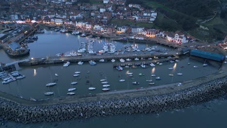 Aerial-forward-shot-of-boats-parked-at-the-Scarborough-harbor-during-night-time-in-England