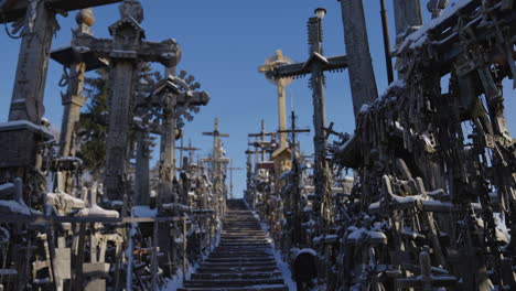 Antiguas-Cruces-Religiosas-Con-Un-Hermoso-Punto-De-Fuga-Y-Un-Paisaje-Al-Fondo,-En-La-Colina-De-Las-Cruces-En-Lituania,-Filmación-Cinematográfica-En-Cámara-Lenta