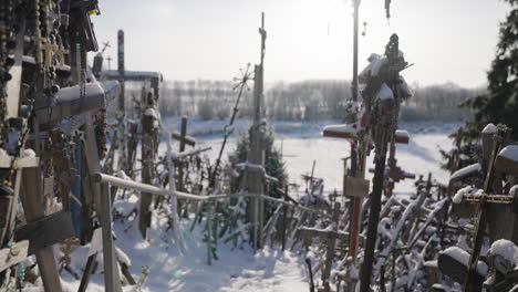 Viele-Kreuze-Angesammelt-Und-Aufgestapelt,-Alte-Religiöse-Kreuze-Mit-Rosenkränzen-Im-Gegenlicht-Mit-Den-Sonnenstrahlen,-Unter-Blauem-Himmel,-Im-Winter,-Filmische-Aufnahme-In-Zeitlupe