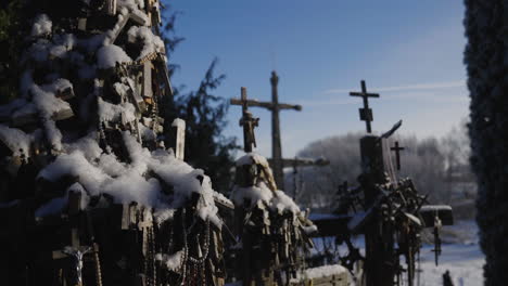 Ancient-Christian-crosses-in-the-middle-of-the-forest-surrounded-by-pines-and-trees,-illuminated-by-the-sun's-rays-in-a-close-up,-under-a-blue-sky,-cinematic-shot-in-slow-motion