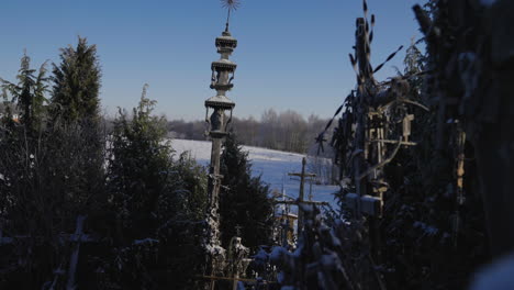 Hermoso-Y-Antiguo-Pilar-Católico-En-La-Colina-De-Las-Cruces-En-Lituania-Entre-La-Nieve,-Los-árboles-Y-El-Invierno