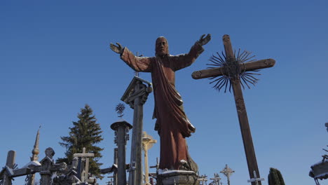 Beautiful-sculpture-of-Jesus-Christ-preaching,-surrounded-by-crosses-on-the-Hill-of-Crosses-in-Lithuania-in-the-middle-of-winter