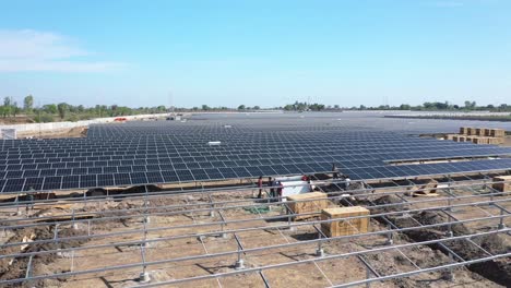 Aerial-drone-view-heading-towards-lots-of-solar-panels-and-lots-of-bushes-and-power-stations-around