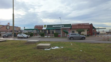 Imágenes-Panorámicas-Del-McDonald&#39;s-En-La-Entrada-De-Jumbo-Plaza-Con-Autos-Entrando-Y-Pasando,-En-Un-Día-Nublado