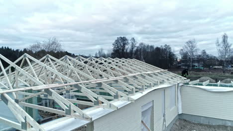 Drone-flying-low-over-a-wooden-roof-frame-project-site-on-a-neighborhood-house