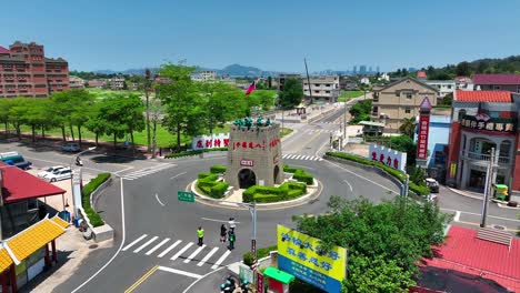 Vista-Aérea-De-Personas-Caminando-En-La-Rotonda-De-Kinmen-Y-Observando-El-Famoso-Monumento-De-Guerra-Con-La-Bandera-Ondeante-De-Taiwán