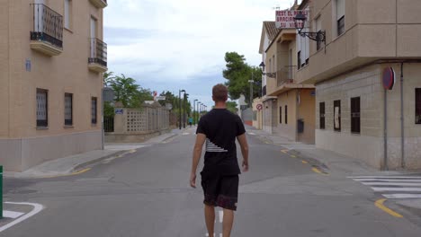 Vista-Posterior-De-Un-Joven-Caminando-En-Medio-De-La-Calle,-Abriendo-Sus-Brazos-Felizmente,-Valencia.