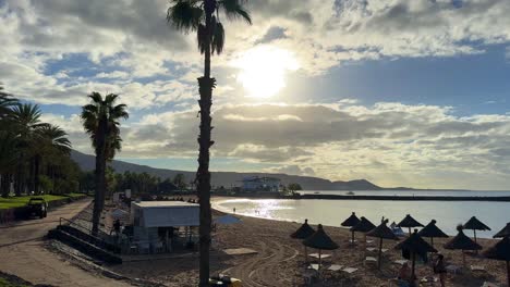 Sunny-beach-in-Playa-de-las-Americas-Tenerife,-calm-waves,-sandy-beach-with-sunbeds