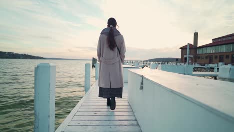 Mujer-Asiática-Caminando-Por-El-Muelle-Hacia-El-Agua-Del-Lago-Al-Atardecer-En-Cámara-Lenta-De-La-Fría-Noche-De-Otoño