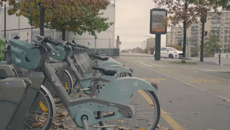 Un-Hombre-Empuja-A-Un-Bebé-En-Un-Cochecito-Entre-Bicicletas-Urbanas-Estacionadas,-Mientras-Otro-Niño-Lo-Sigue