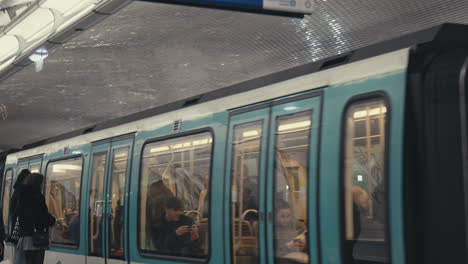 Toma-Panorámica-De-Un-Tren-Que-Llega-A-La-Estación-Subterránea-De-Metro-De-Nation,-Pasajeros-Esperando-Para-Abordar.