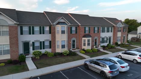 Townhouses-with-brick-facades,-white-trim,-parked-cars,-and-dusk-lighting