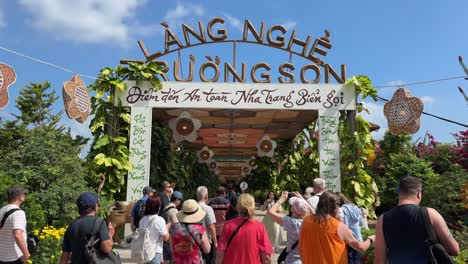 Scene-of-a-group-of-tourists-taking-photos-of-the-entrance-outside-Truong-Son-craft-village-in-Nha-Trang,-Vietnam