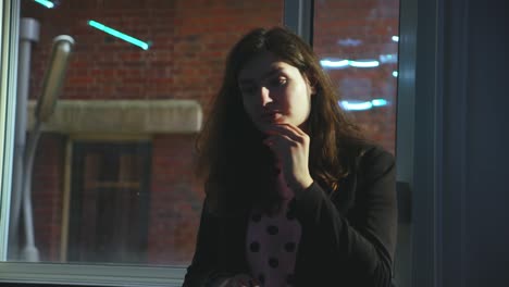 Brown-hair-woman-pondering-and-thinking-while-being-hit-by-sunlight-in-office