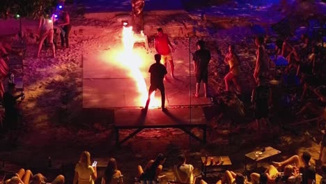 Young-people-drinking-and-taking-turn-jumping-fire-robe-at-Thai-beach-party