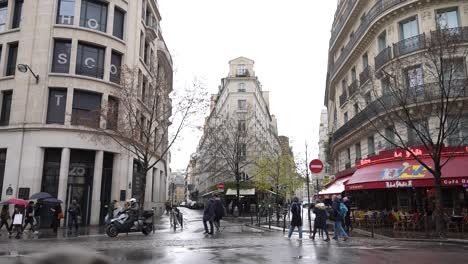 Feydeau-street-with-Hopscotch-Group-building-left-and-La-Java-cafeteria-right-during-rainy-day,-Handheld-wide-shot