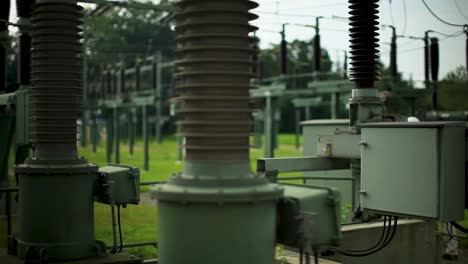 Electrician-in-high-visibility-vest-inspecting-equipment-at-power-station,-daytime