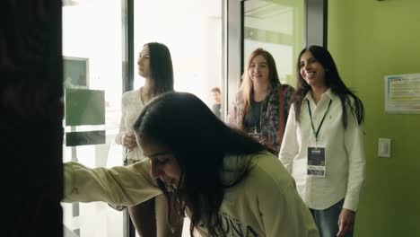 A-small-group-of-young-woman-female-students-laugh-and-smile-as-they-interact-with-a-piece-of-display-technology-at-a-university-campus-trade-show-in-Toronto-Ontario-Canada