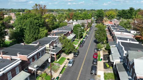 Vista-Aérea-De-Una-Calle-Residencial-Arbolada-Con-Casas-En-Hilera-Y-Autos-Estacionados