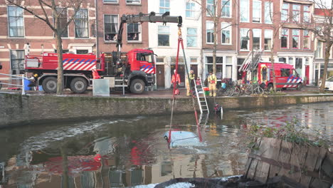 Feuerwehrleute-Ziehen-Mit-Einem-Mobilkran-Ein-Auto-Aus-Dem-Zugefrorenen-Stadtkanal