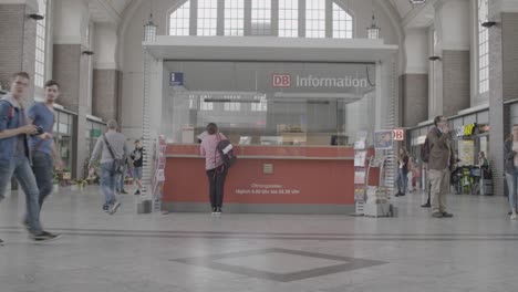 Passagiere-Laufen-An-Einem-DB-Informationsschalter-In-Einem-Belebten-Bahnhof-Vorbei