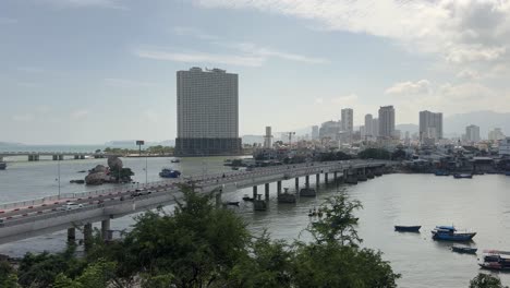 Sich-Bewegende-Fahrzeuge-Auf-Der-Brücke-Und-Vor-Dem-Wunderschönen-Hintergrund-Der-Stadtlandschaften-In-Nha-Trang,-Vietnam