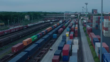 Crepúsculo-Sobre-Una-Concurrida-Estación-De-Tren-De-Carga-Con-Paseos-De-Seguridad-Y-Numerosos-Contenedores-De-Carga-Coloridos