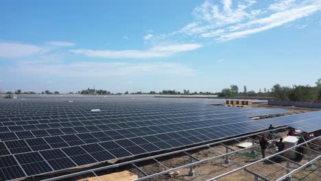 Vista-Aérea-De-Drones-Cámara-Del-Teléfono-Avanzando-Donde-Muchos-Hombres-Están-Quitando-Y-Colocando-Paneles-Solares-De-Cajas-Se-Ven-Muchas-Cajas-Siendo-Colocadas