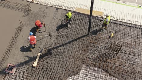 Trabajadores-Con-Chalecos-De-Seguridad,-Cimientos-De-Hormigón,-Barras-De-Refuerzo,-Vierten-Mortero-De-Cemento-Sobre-Malla-De-Refuerzo-O-Jaula-De-Bomba-Hormigonera